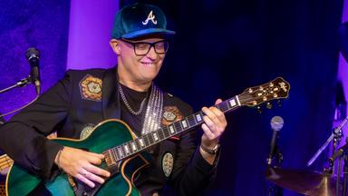 Mann steht mit Gitarre auf der Bühne