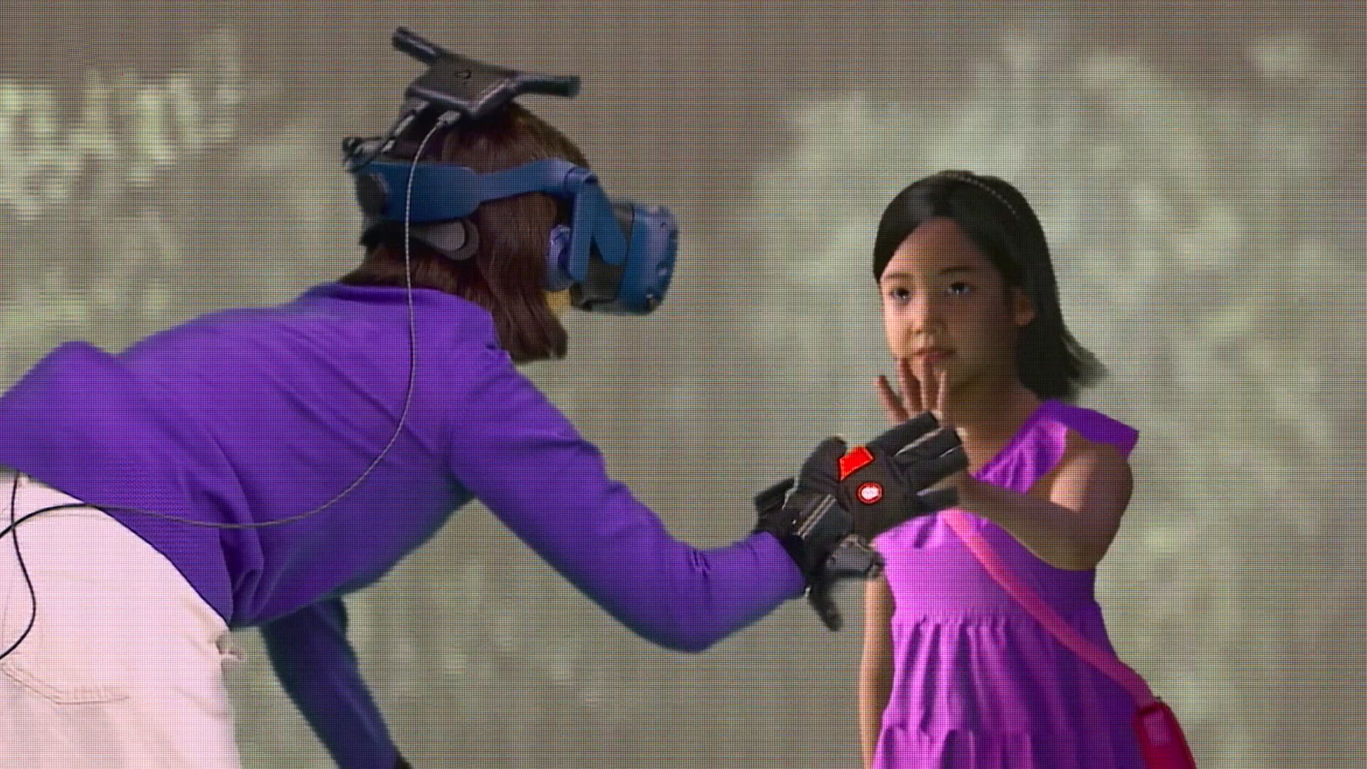 Eine Person mit VR-Headset und Datenhandschuh interagiert mit einem digitalen Hologramm eines Mädchens in einem pinkfarbenen Kleid.