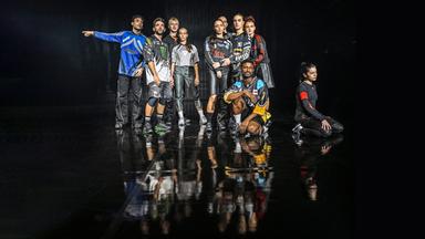 Gruppenbild des ensembles in Sporttrikots. Hinten stehen zwei Vierergruppen. Vor der rechten Gruppe kniet ein Mann und rechts neben dieser Gruppe kniet eine Frau, die zur Seite schaut.