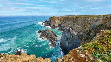 Damatische Steilküste an der Algarve: Tosende Atlantikwellen brechen unterhalb der schroffen Felsen Portugals.