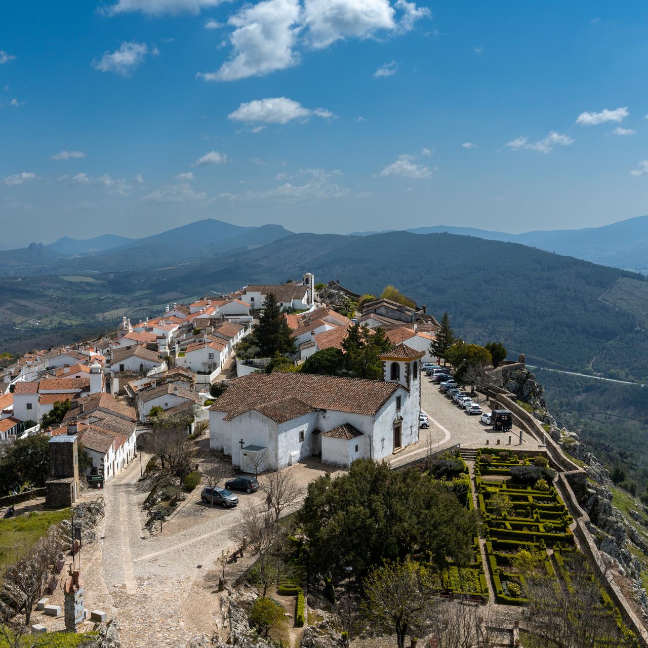 Blick auf die historische Altstadt von Marvao mit Kirche und Schlossgarten. Im Hintegrund grüne Hügel.
