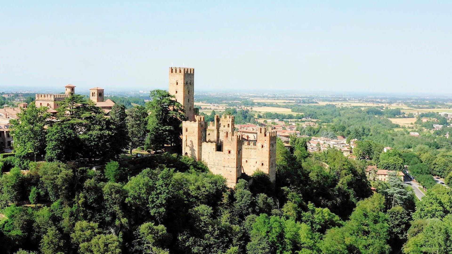 Die mittelalterliche Burg Rocca Viscontea liegt auf einem bewaldeten Hügel.
