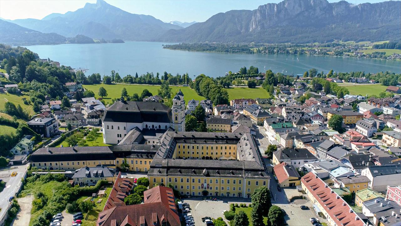 Blick auf große Schlossanlage und den dahinter liegenden See