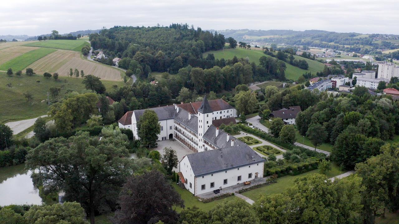 Luftaufnahme von Schloss Parz in Grieskirchen, einem beeindruckenden Renaissanceschloss mit angrenzenden Gärten und umgeben von grünen Feldern.