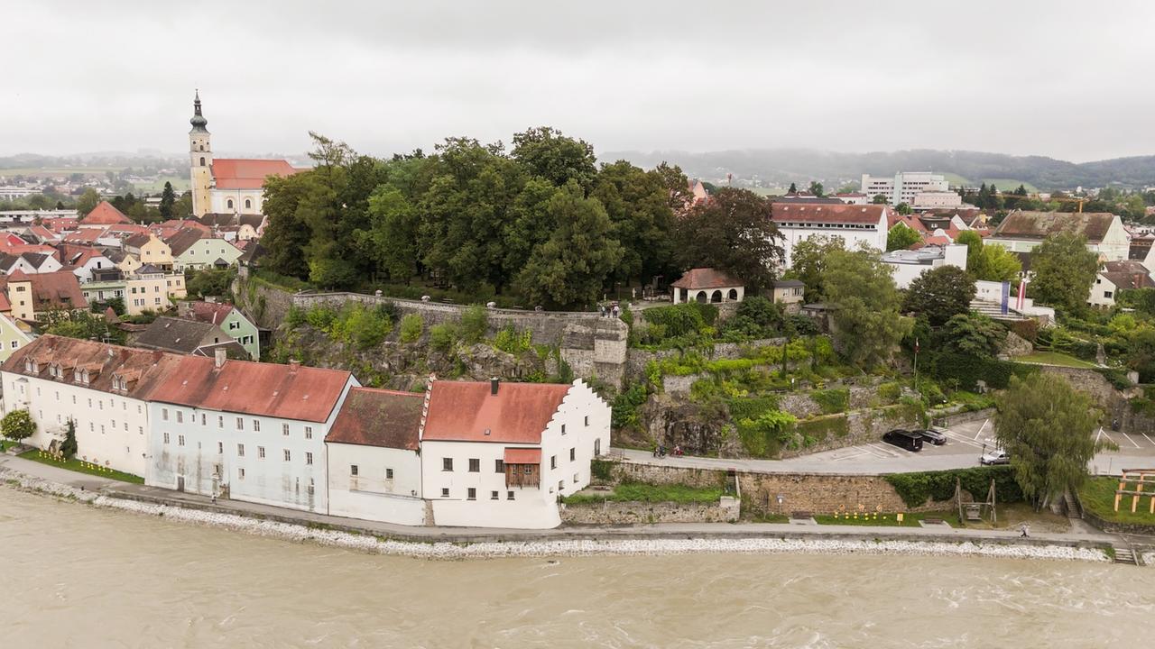 Luftaufnahme von Burg Schärding, einer historischen Burg in der Stadt Schärding mit erkennbaren Mauerzügen und einem Burggraben.