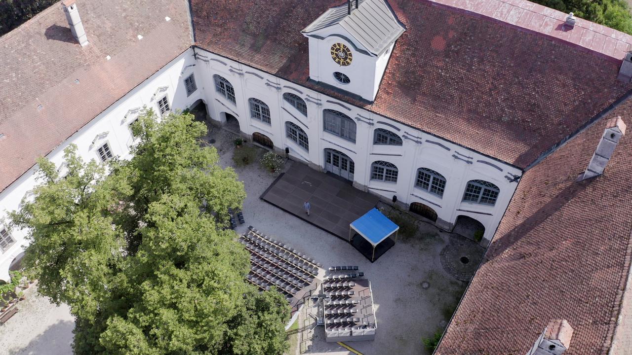 Luftaufnahme der Innenansicht von Schloss Tillysburg, die einen Innenhof mit Sitzreihen für Veranstaltungen zeigt, umgeben von den Mauern des historischen Schlosses.