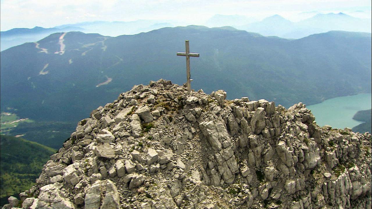 Schmaler Berggipfel mit Geröll, darauf Bergkreuz
