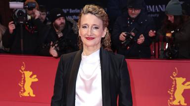 Frau steht auf rotem Teppich und schaut lächelnd in die Kamera.