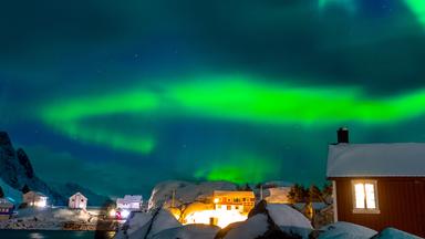 Grüne Polarlichter über einem Dorf in Skandinavien. 