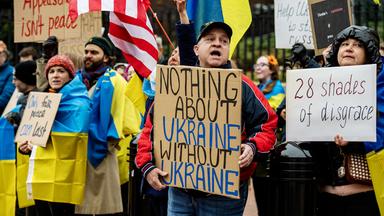 Demonstranten mit gelb-blauen ukrainischen Flaggen halten Plakate hoch, auf denen sie einen Mitbestimmung der Ukraine bei Friedensverhandlungen fordern.