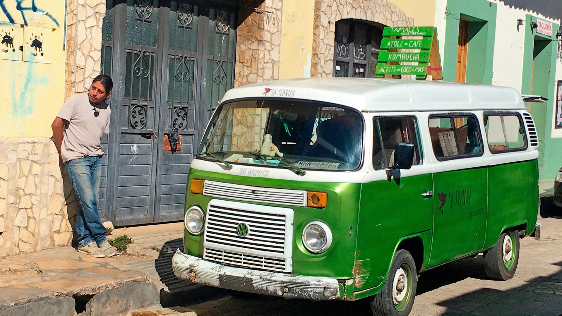 Edgar Coronado de Léon lehnt an einer Hausmauer, vor ihm steht sein Foodtruck-Bulli.