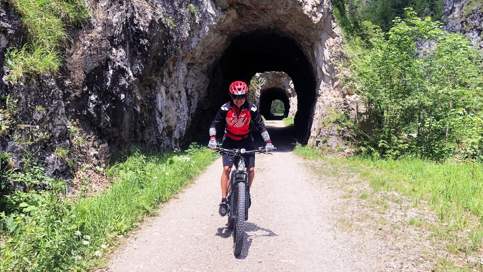 Eine Frau auf einem Mountainbike vor einem Steindurchgang.
