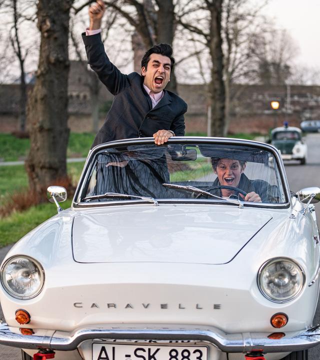 Zwei junge Männer in einem alten Cabrio.