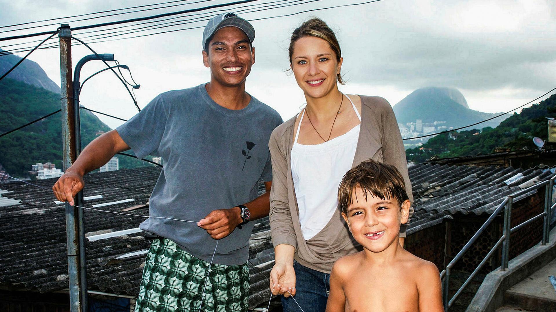 Die Moderatorin steht neben einem Barsilianer, vor ihr ein kleiner brasilianischer Junge