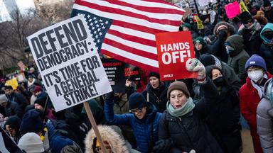Demonstranten schwenken die US-Flagge und tragen Schilder, auf denen aufgerufen wird, die Demokratie zu verteidigen.