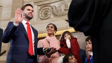 Ein Mann im Anzug hebt die rechte Hand zum Schwur, die linke hat er auf eine Bibel gelegt, die seine Frau für ihn hält. Auf dem anderen Arm trägt sie ein Mädchen und vor dem Paar stehen zwei kleine Jungen.