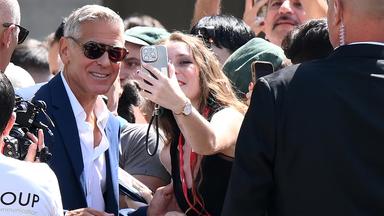 In einer Menschenmenge macht eine Frau ein Selfie mit einem gut aussehenden Mann mit Sonnenbrille.