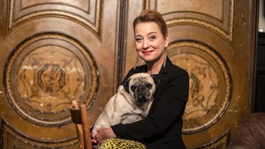 Frau mit Hund auf einem Stuhl sitzend.