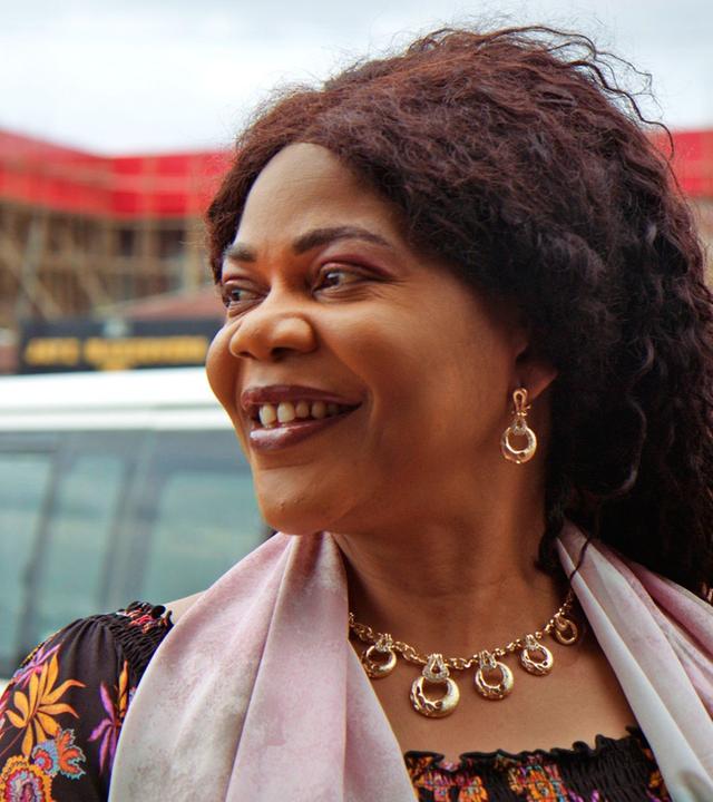 Eine Frau lächelt an der Kamera vorbei. Im Hintergrund weitere Frauen