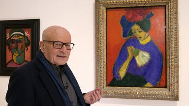 Ein älterer Mann steht neben einem gemalten Bild einer Frau mit Hut und Fächer.