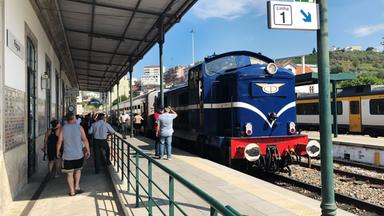 Ein blauer Zug fährt in einen kleinen Bahnhof ein.