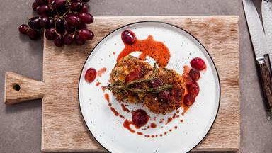 Knödel mit würzigem Schafskäse auf einem fruchtigen Ragout aus Weintrauben auf einem Teller.