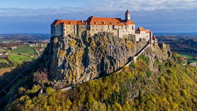 Auf einem hohen Berg gelegene Burg vor blauem Himmel