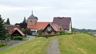 Fachwerkhäuser stehen an einem Deich