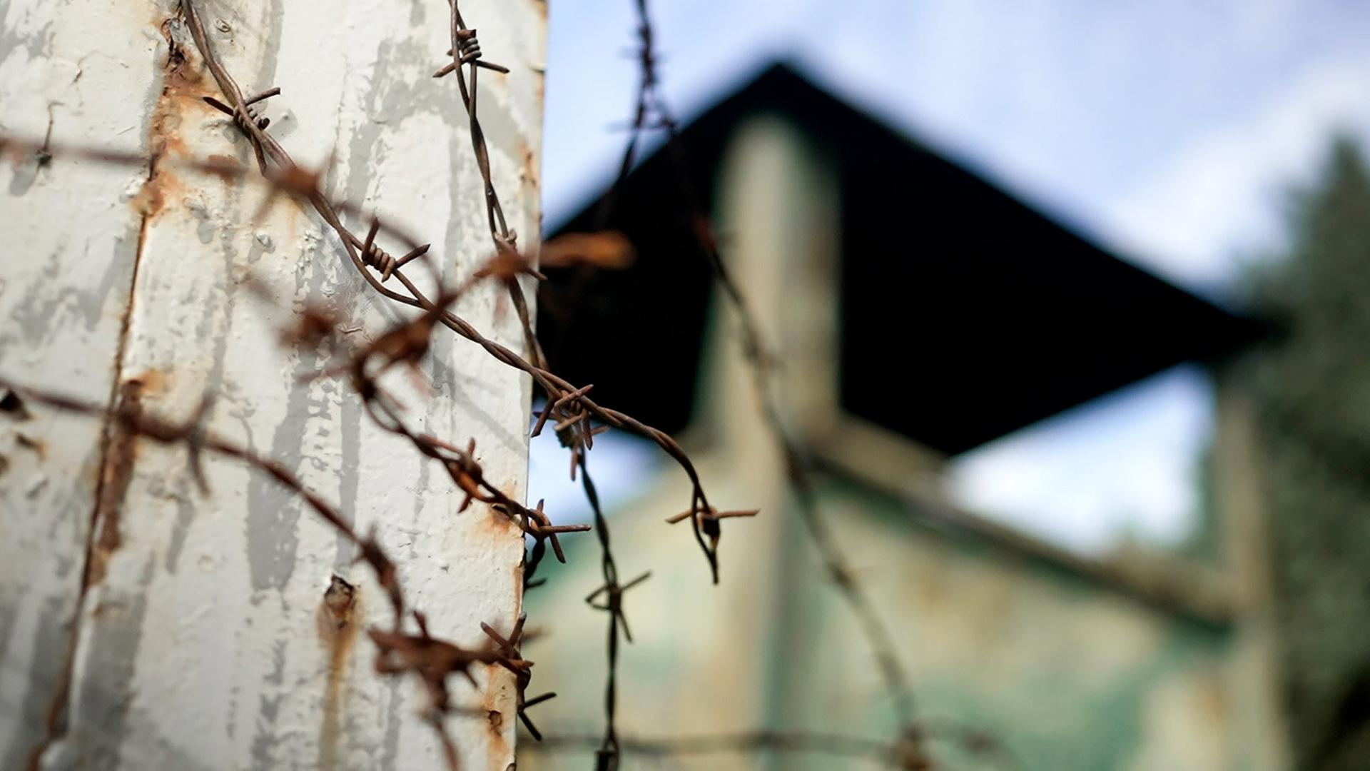 Rostiger Stacheldraht mit einer unscharfen Bunkerstadt im Hintergrund