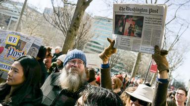 Demonstranten halten ein Exemplar der Zeitung Washington Post und Plakate hoch.