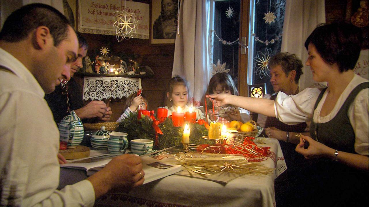 Familie um den Hüttentisch bei Kerzenglanz.
