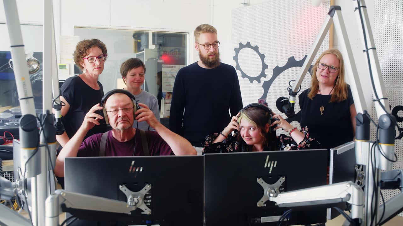 Eine Gruppe von Radiomachern nimmt an einem Workshop im Freien Radio radiofabrik in Salzburg teil. Einige sitzen vor Computern und tragen Kopfhörer.