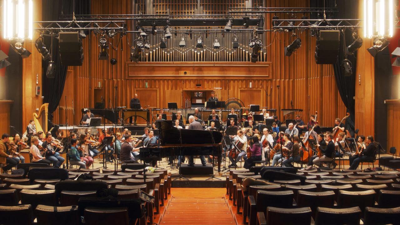 Der Komponist HK Gruber dirigiert das Radiosymphonieorchester bei Aufnahmen im Radiokulturhaus. Vorne in der Mitte steht ein Flügel.