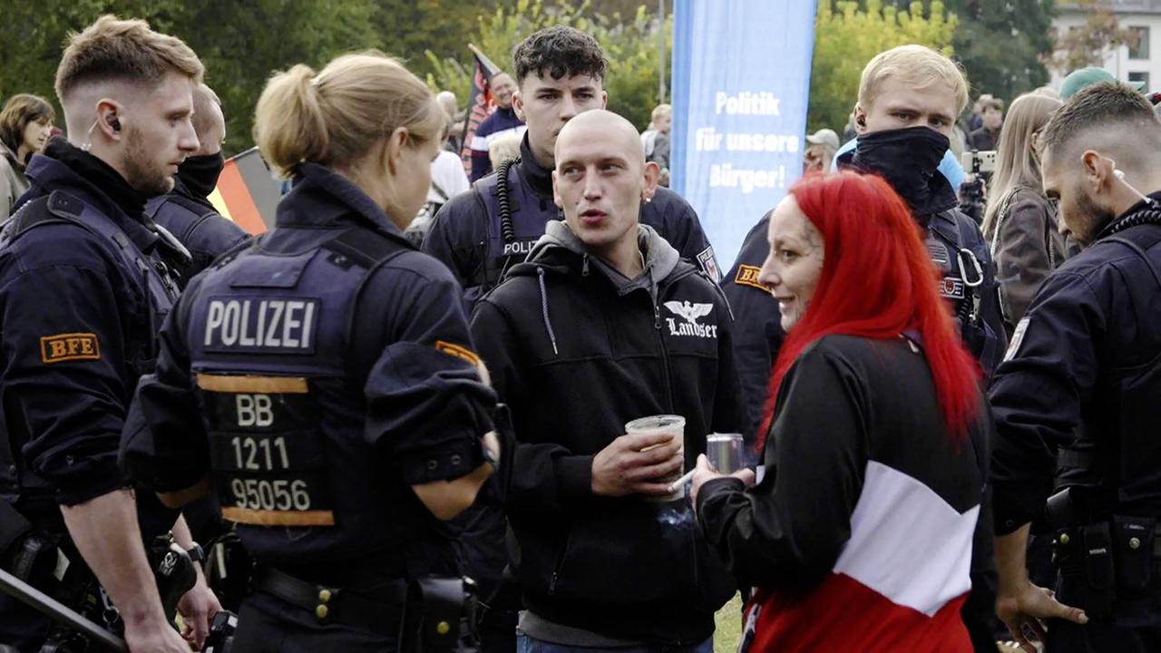 Polizisten umringen mehrere junge Leute, die zum Teil vermummt sind.