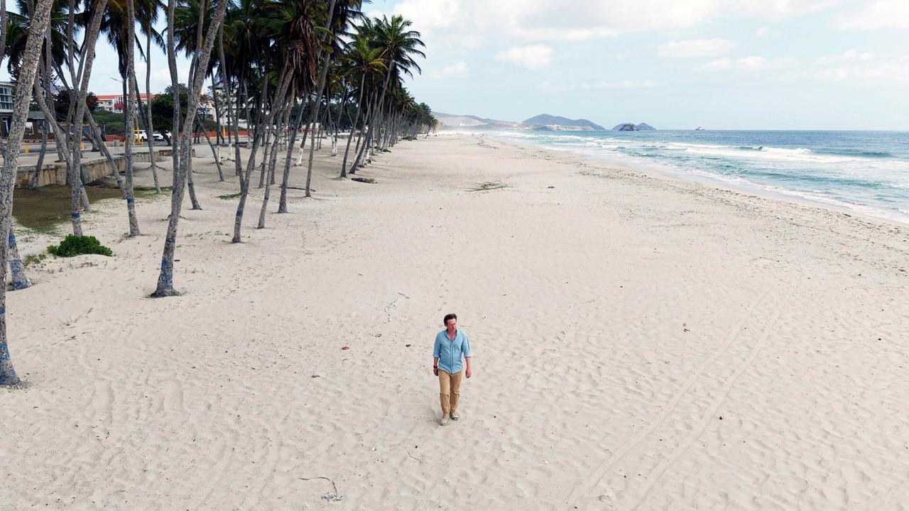 Ein Mann allein an einem menschenleeren Strand.