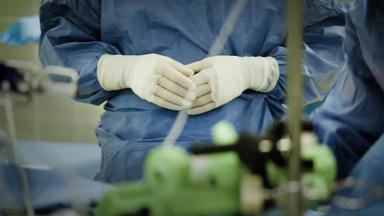 Nahaufnahme der Hände einer Person in OP-Kleidung.