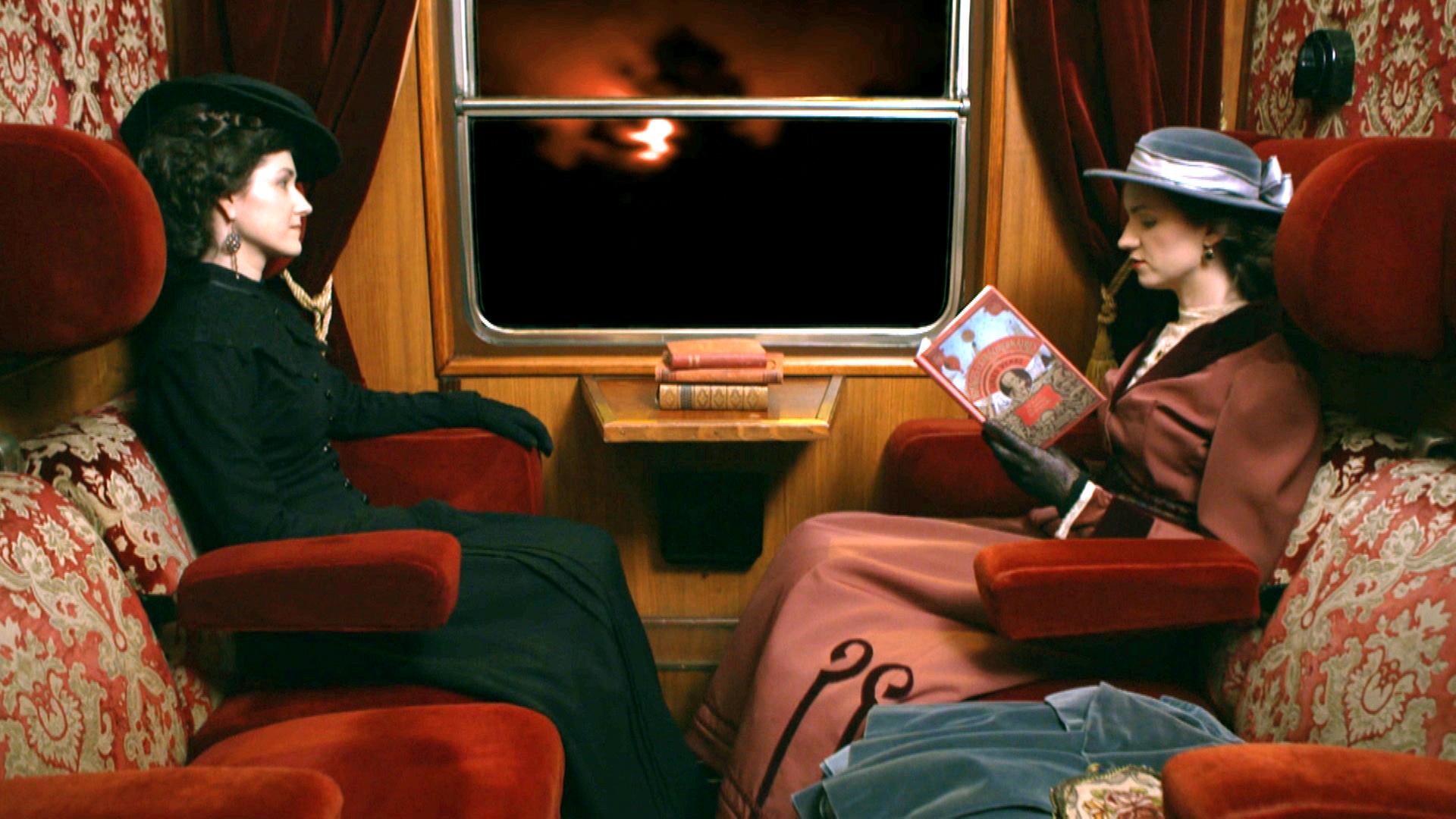 Zwei historisch gekleidete Damen im Zugabteil des Orientexpresses vor dem Fenster.