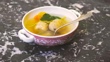 Eine Suppenschüssel mit Matzeknödlsuppe und einem Löffel.