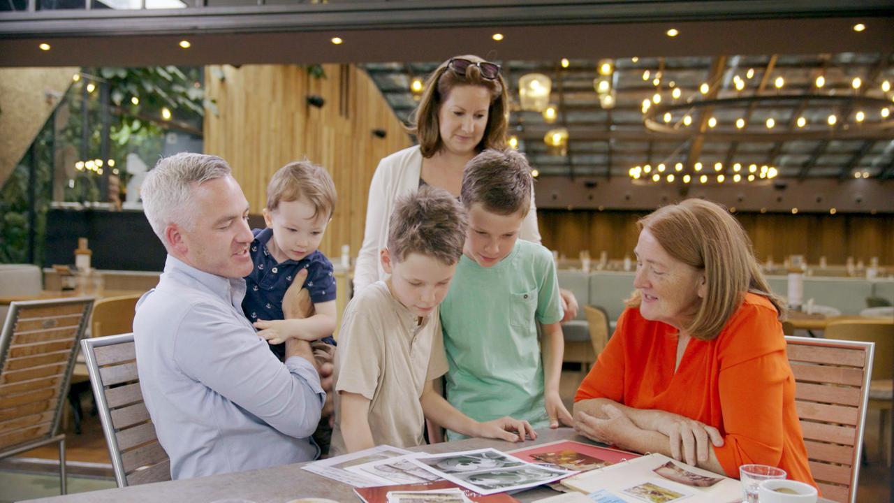 Drei Erwachsene und drei Kinder schauen sich auf dem Tisch Bilder an