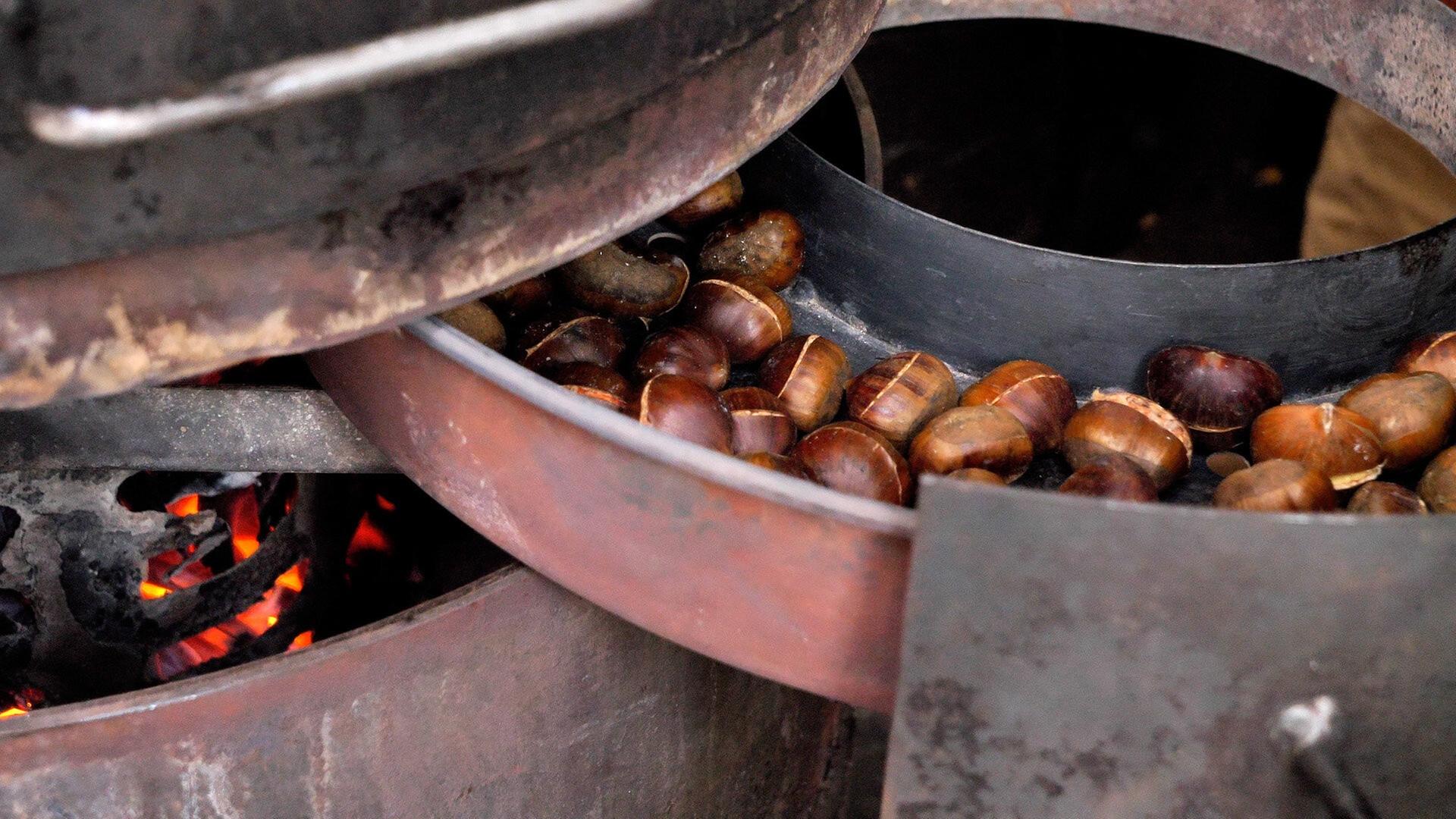Maroni-Ofen mit glühenden Kastanien auf einem Wiener Markt, Symbol für das winterliche Stadtbild.
