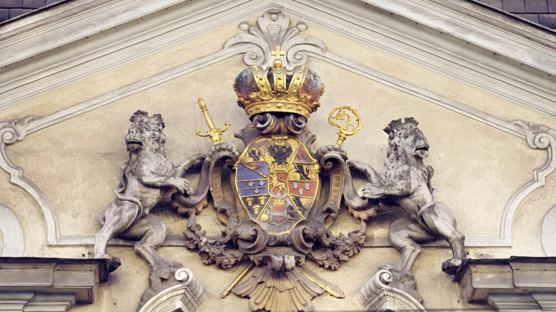 Steinlöwen halten das Wappen mit goldener Krone