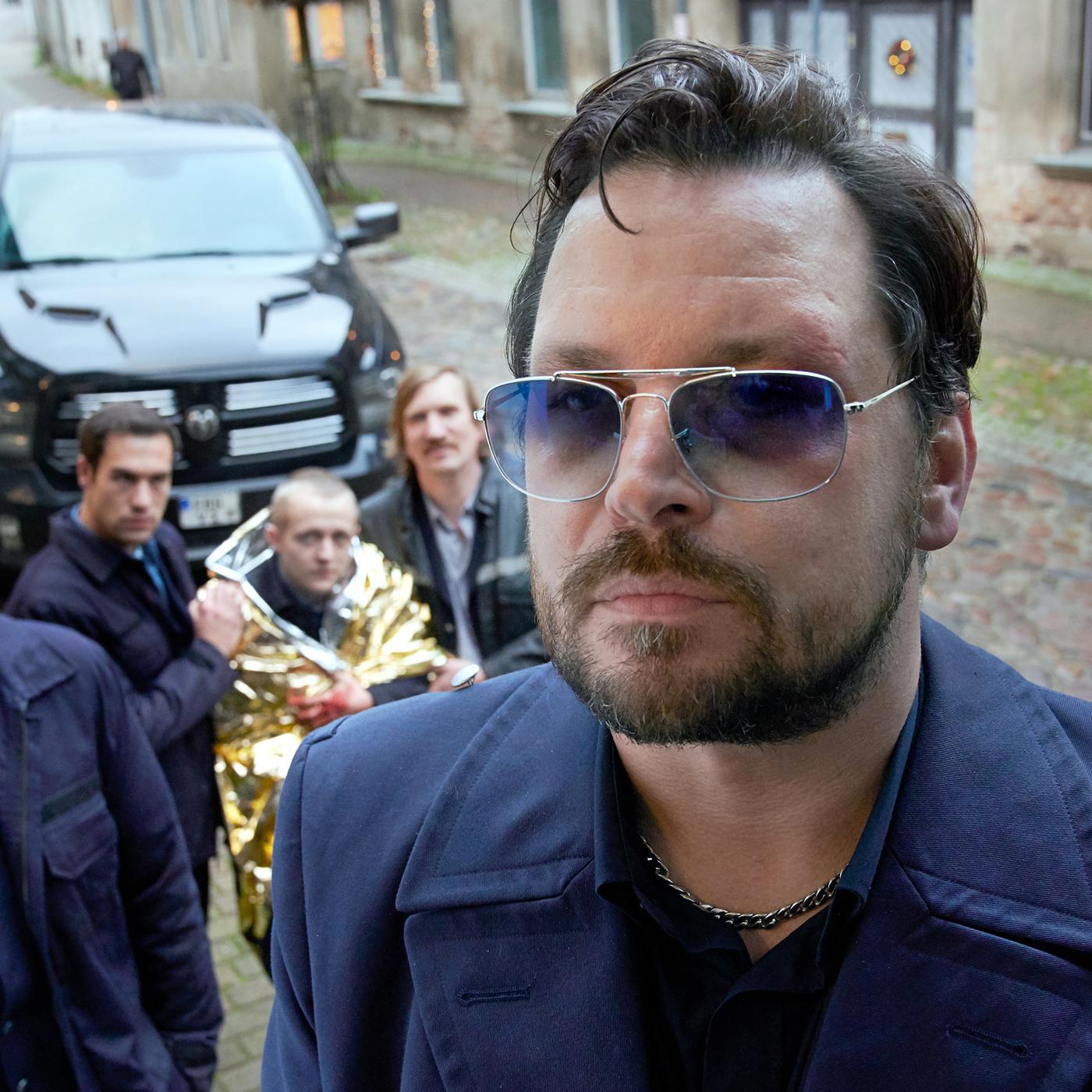 roßaufnahme Herrmann (Sascha Alexander Geršak) auf Türschwelle mit Thoralf (Roman Schomburg), Ronny (Malte Thomsen), Steffen (Jakob Schmidt), Norbert (Karten Mielke) und SUV in Hintergrund