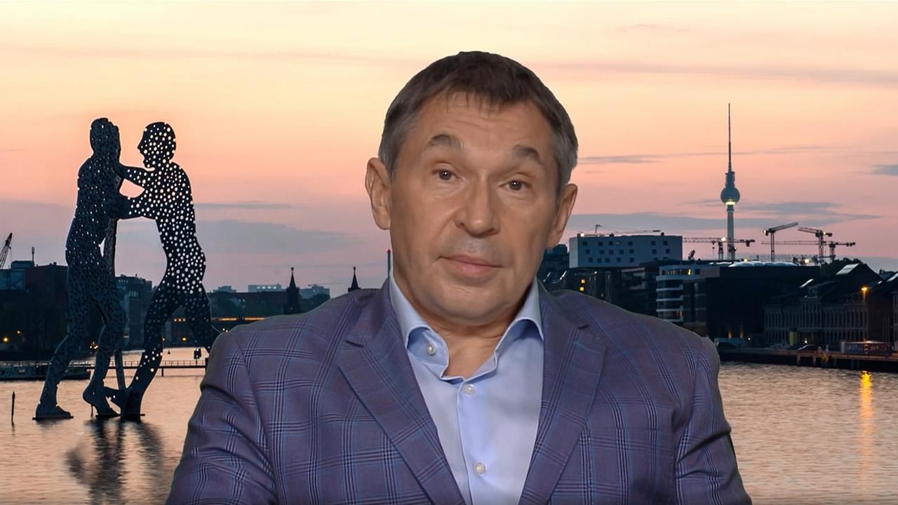 Ein Mann mit kurzem gräulichen Haar und einem Anzug vor dem Hintergrund Berlins