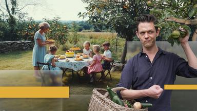 Jo Schück mit Apfelkorb und Familie am Gartentisch in grüner Idylle