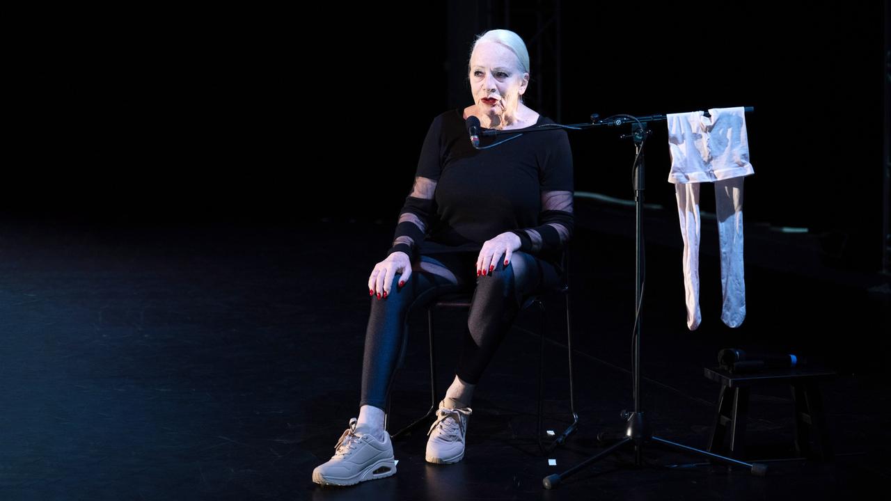 Eine schwarz gekleidete Frau vor schwarzem Hintergrund