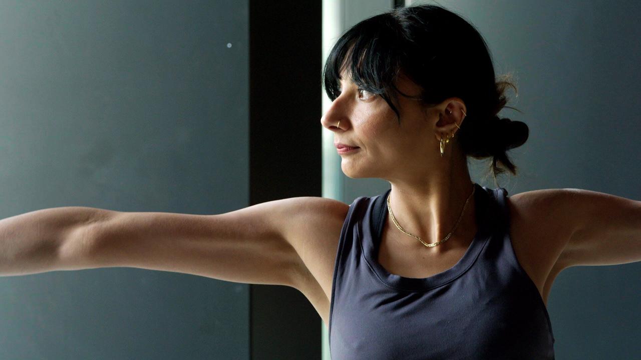Eine Frau im Profil führt eine Yoga-Position aus.