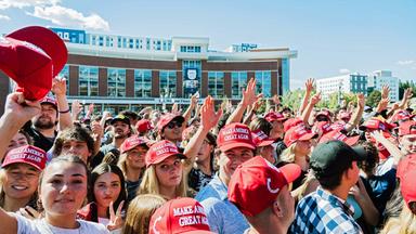 Eine Gruppe junger Menschen trägt rote Kappen mit der Aufschrift Make Amerika Great Again.
