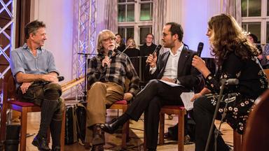 Die Wells, Helge Schneider und Igor Levit sitzen auf Stühlen und sprechen in Mikrofone.