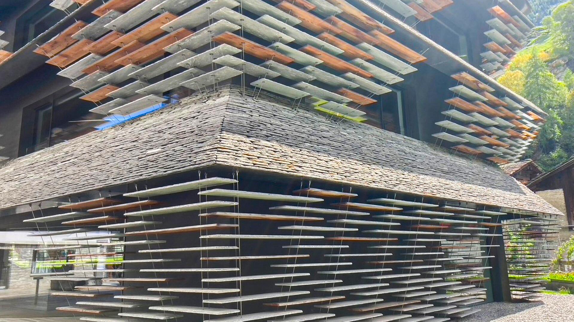Geschäftshaus mit Fassade aus scheinbar schwebenden Steinplatten, die an Drahtseilen befestigt sind