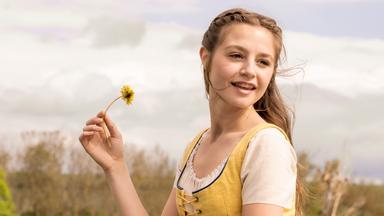 Eine junge Frau mit einem Löwenzahn.